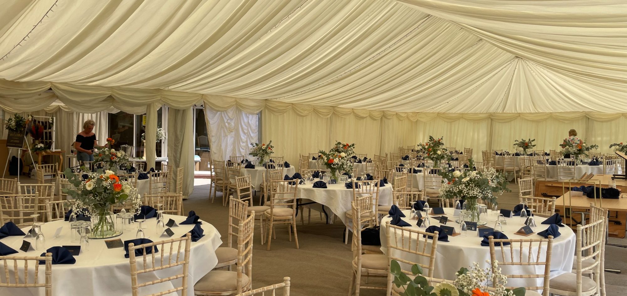 Elegant wedding banquet setup in a marquee hired with decorated tables and floral centrepieces.